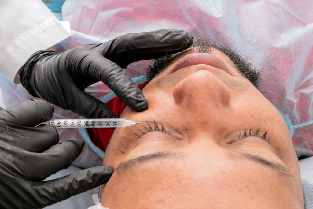 Man receiving facial treatment with syringe in medical facility.