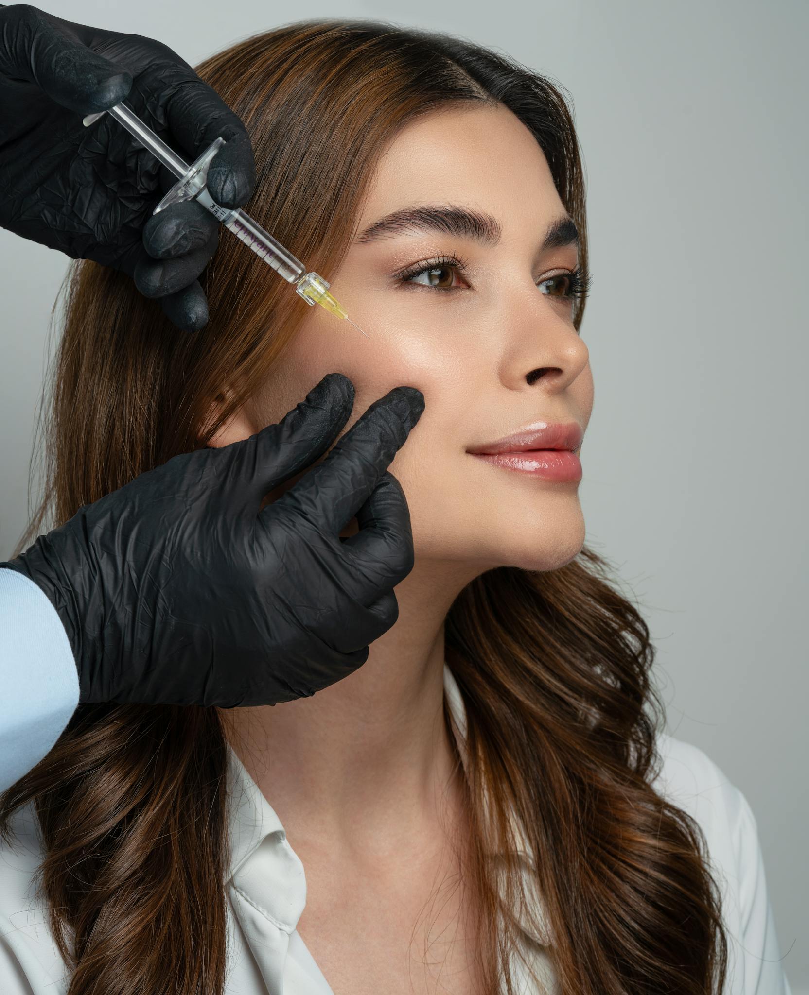 A dermatologist administers a dermal filler injection to a woman's face, enhancing facial aesthetics.