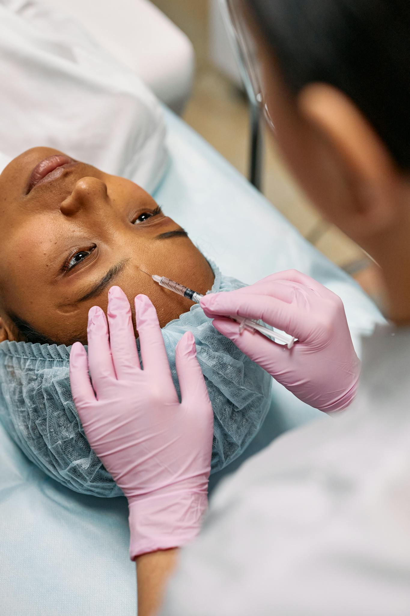 Close-up of a cosmetic professional administering a Botox injection on a patient's forehead in a clinic.